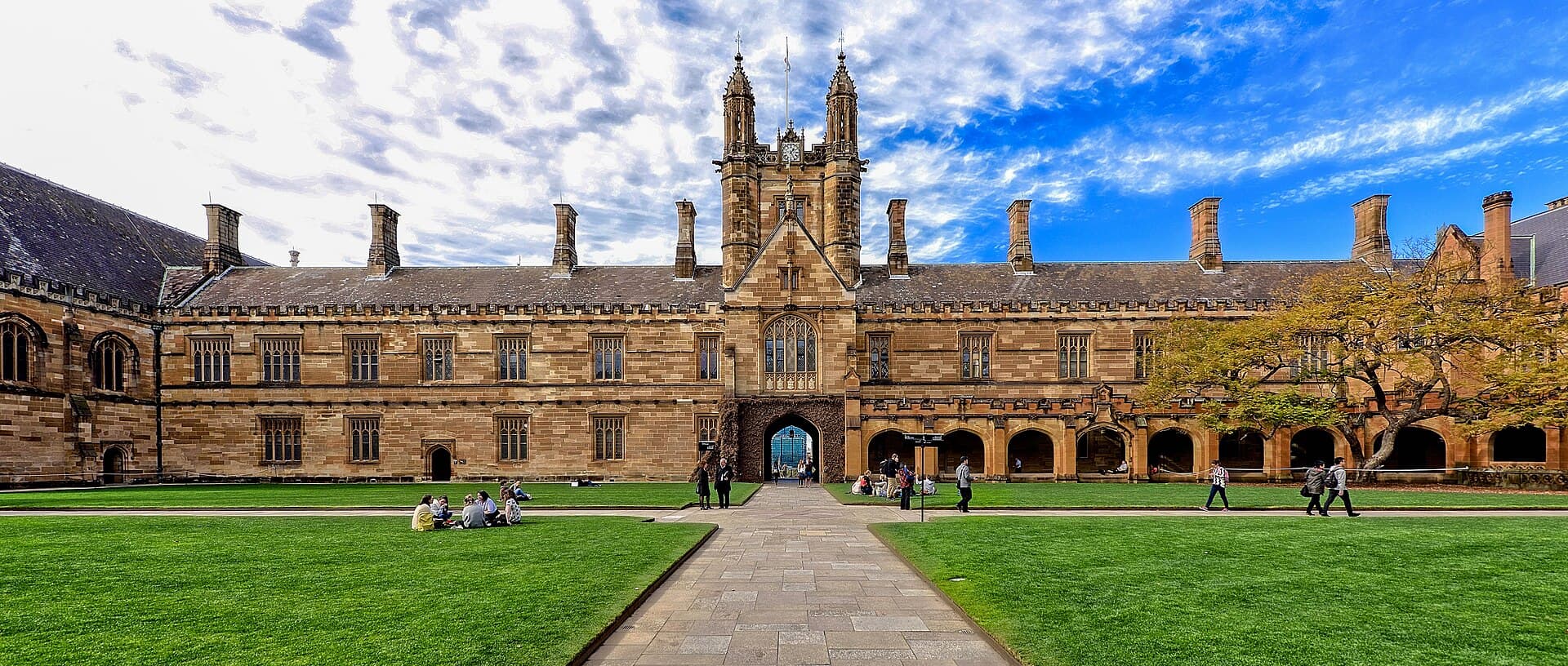 The sandstone Main Quadrangle at the University of Sydney with students on the lawn