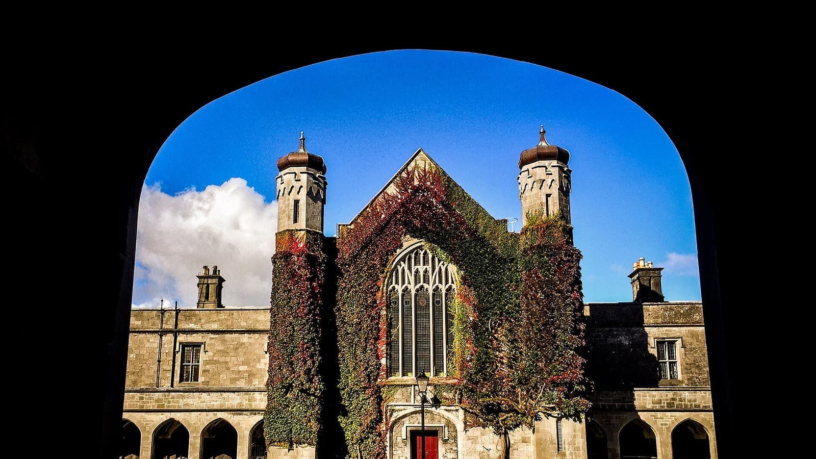 The ivy-covered Quadrangle building at the University of Galway, framed through a stone archway