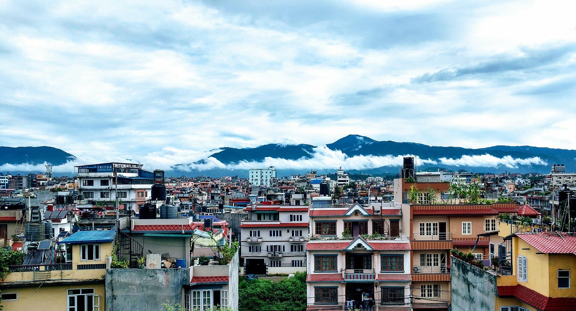 Kathmandu rooftops at morning with college buildings and the Shivapuri hills behind