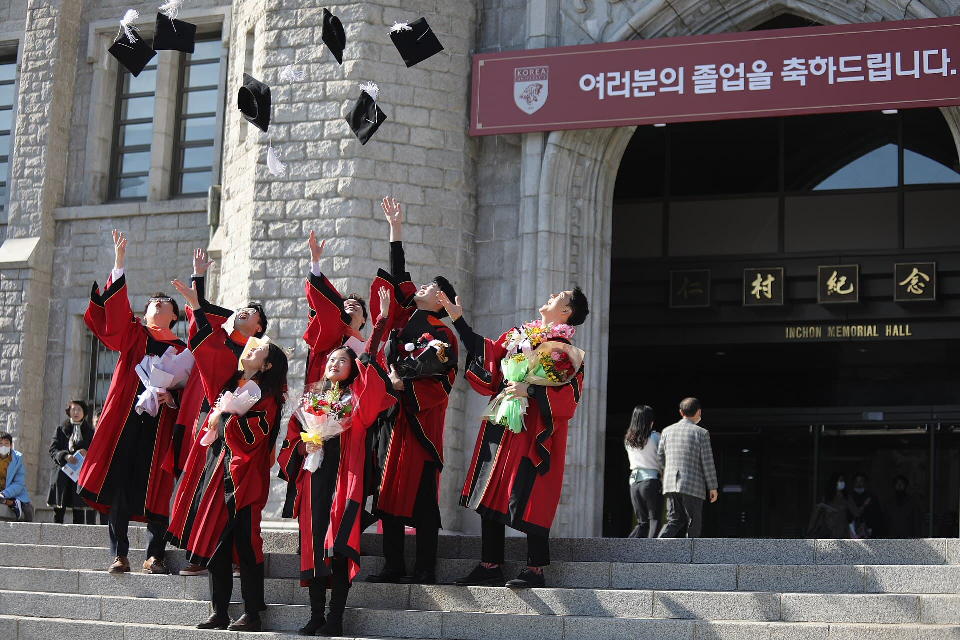 Graduating students in red gowns throwing their caps in the air